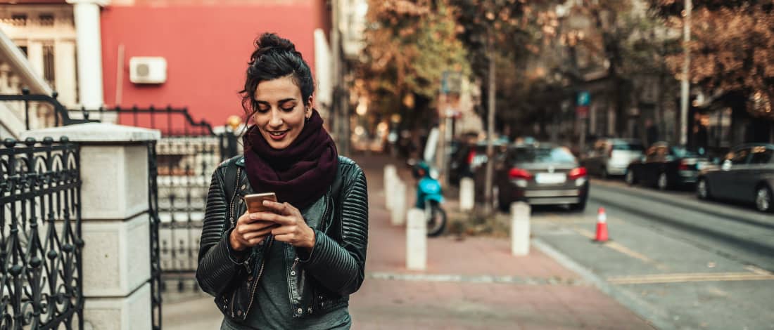 Woman with a smartphone walking on the side walk